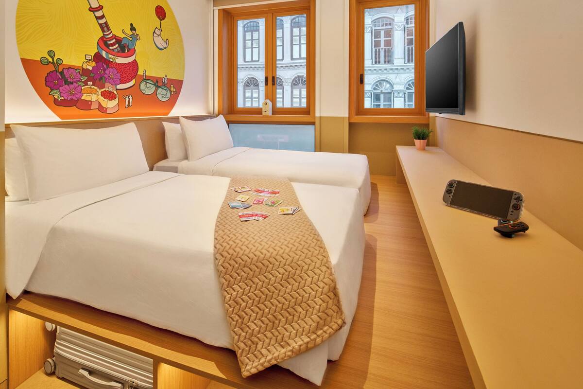 Een hotelkamer met een bed, een bureau, een televisie en een raam met uitzicht op gebouwen.