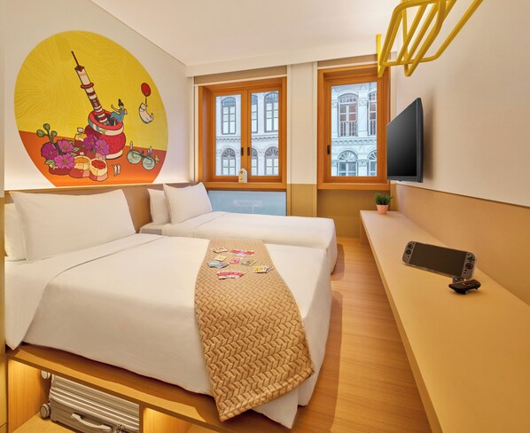 A hotel room with a bed, a desk, a TV, and a window with a view of buildings.
