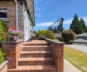 A brick staircase leading to a building entrance, surrounded by greenery and flowers. - Bright Private 3BR/2BA Main-Level Home Near BeckwithPark,Victoria Patio& Parking (Victoria)