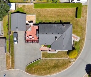 An aerial view of a residential area with a house, a driveway, a car, and a small garden.