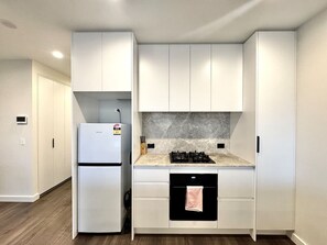 A modern kitchen with white cabinetry, a built-in stove, and a dishwasher. - 2BR 2BA Modern Manor House - Steps from Monash Uni (Clayton)