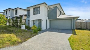 A modern two-story house with a garage, a driveway, and a well-maintained lawn.