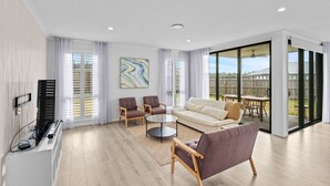 A modern living room with a sofa, two armchairs, a coffee table, and a TV.
