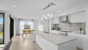 A modern kitchen with a central island, stainless steel appliances, and a dining area with yellow chairs.