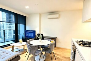 A modern apartment with a dining area, kitchen, and large windows offering a city view. - Free Tram Zone - Lighthouse Apt near Vic Market (Melbourne)