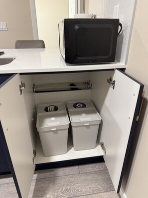 Une cuisine équipée d’un four à micro-ondes, de deux poubelles et d’un évier.