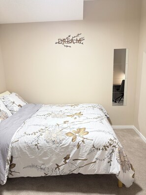 Un dormitorio con una cama, un espejo montado en la pared y la palabra 'DREAM' decorativa en la pared.