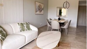 A modern living room with a sofa, dining table, chairs, and a unique coffee table.