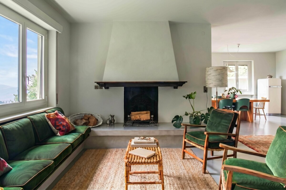 A living room with a fireplace, green sofa, and chairs.