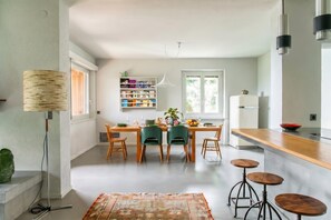 A modern kitchen with a dining table, chairs, a bookshelf, and a bar area. - Luxury Nature Retreat Villa Planchette (Lugano)