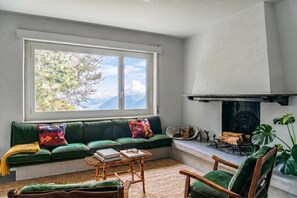 A cozy living room with a green sofa, a wooden coffee table, and a fireplace.