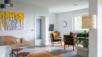 Ein modernes Wohnzimmer mit einer Couch, Sesseln, einem Couchtisch und Kunstwerken an der Wand.