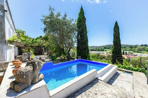 A swimming pool with a stone elephant sculpture, surrounded by greenery and tall cypress trees. - Giardino Orsera With Private Pool (Vrsar)