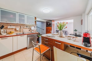 Eine moderne Küche mit weißen Schränken, einer Holz Arbeitsplatte, einem eingebauten Ofen und einem Essbereich mit Stuhl und Tisch.