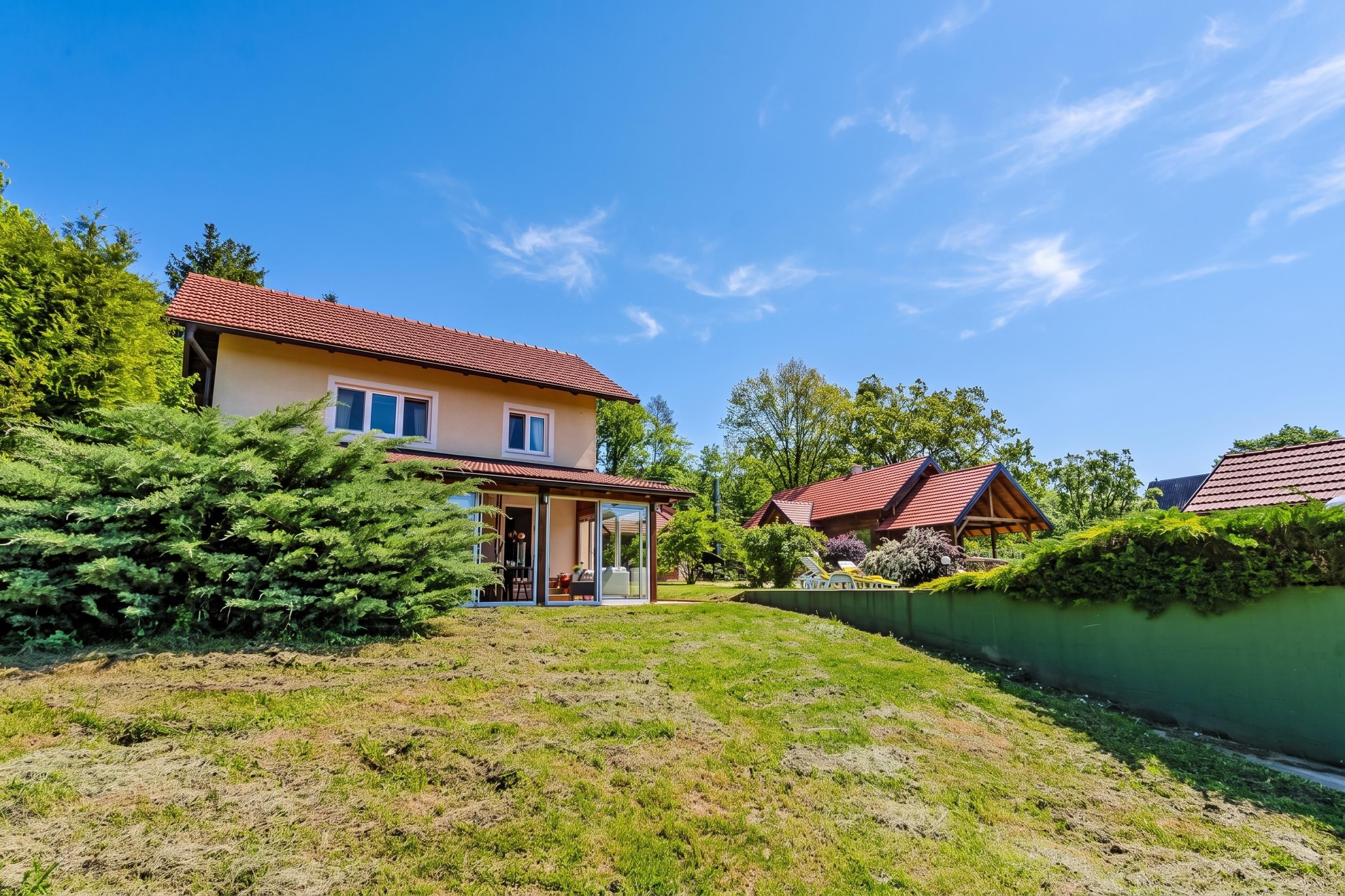 A two-story house with a red-tiled roof, a covered patio, and a well-maintained lawn.