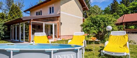 Ein Haus mit Swimmingpool, zwei gelben Liegestühlen und einer überdachten Terrasse.