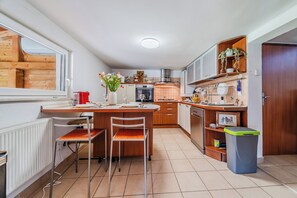 Una cocina compacta con comedor, armarios de madera, horno empotrado y ventana con vistas a una construcción de madera.