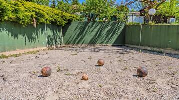 An outdoor area with a gravel surface and a green wall.