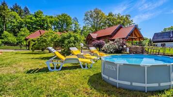 Ein Swimmingpool mit Liegestühlen, umgeben von einer Rasenfläche und Bäumen.