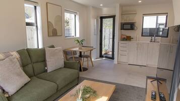 A modern living room with a green sofa, a coffee table, and a dining area with a table and chairs.