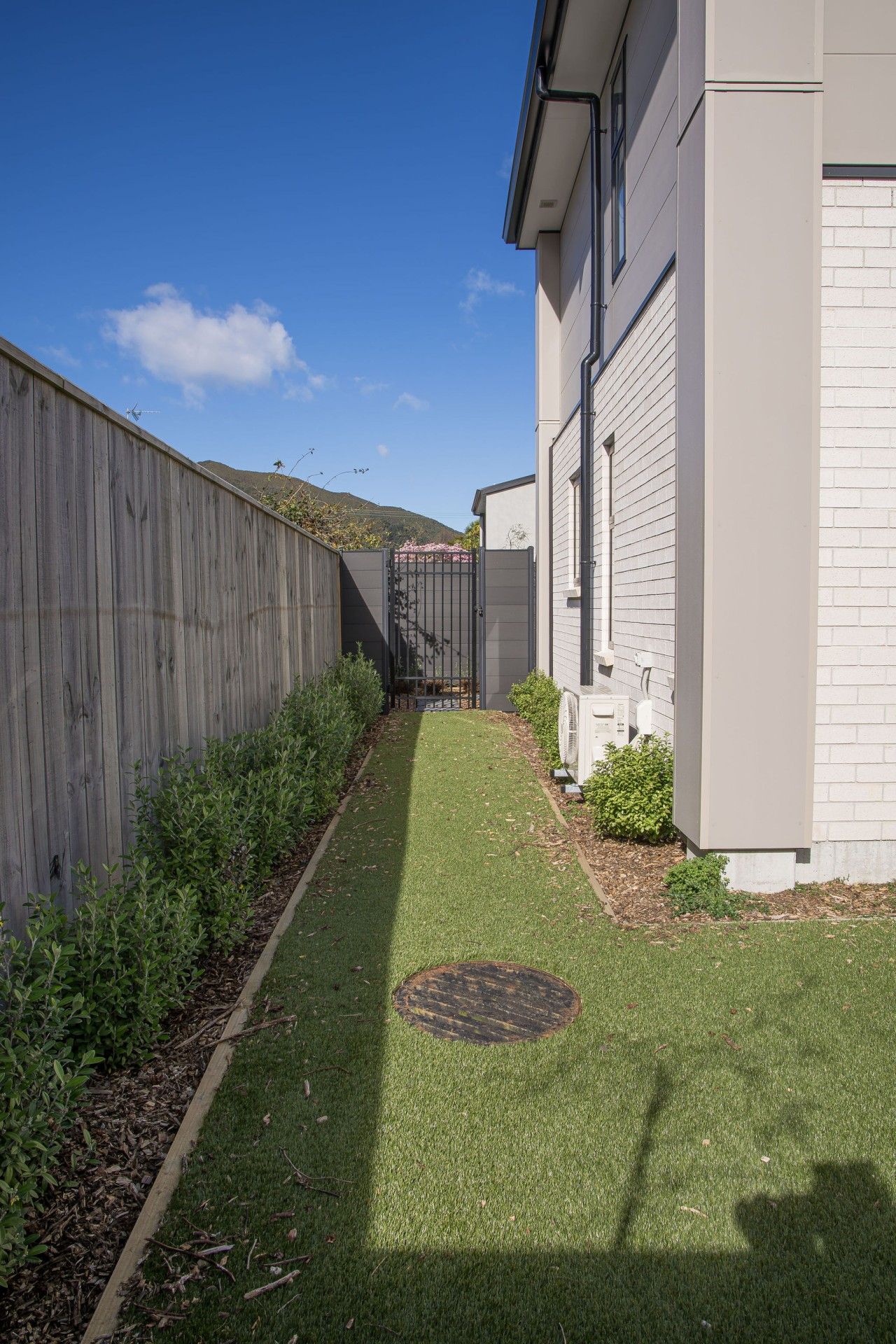 A residential property with a paved pathway, a wooden fence, and a small garden area.