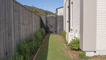 A residential property with a paved pathway, a wooden fence, and a small garden area.