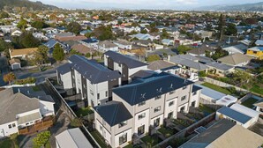 A residential area with modern houses, including a large two-story building with a flat roof and multiple windows.