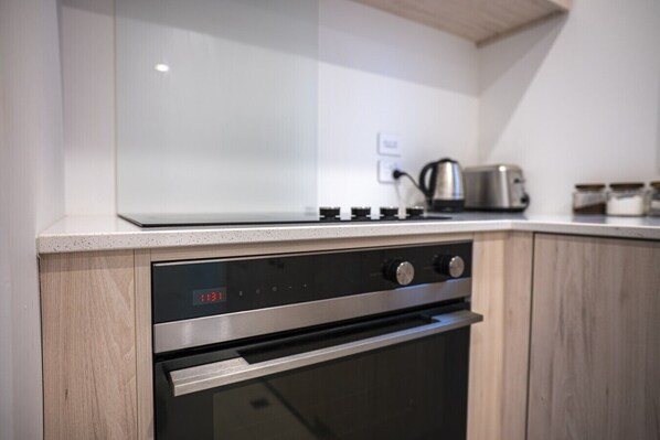 A kitchen with a stainless steel oven, a digital clock displaying 11:31, and a kettle on the countertop.