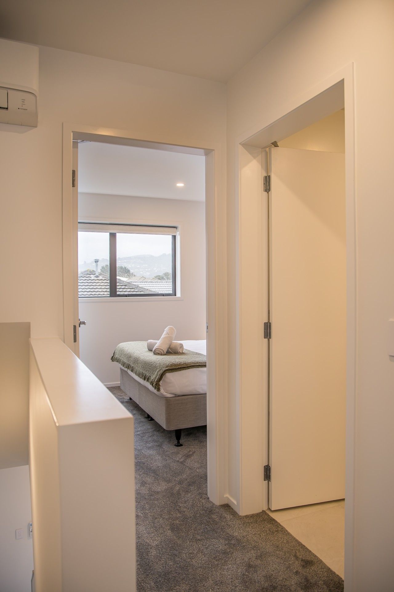 A bedroom with a bed, a window, and a door.