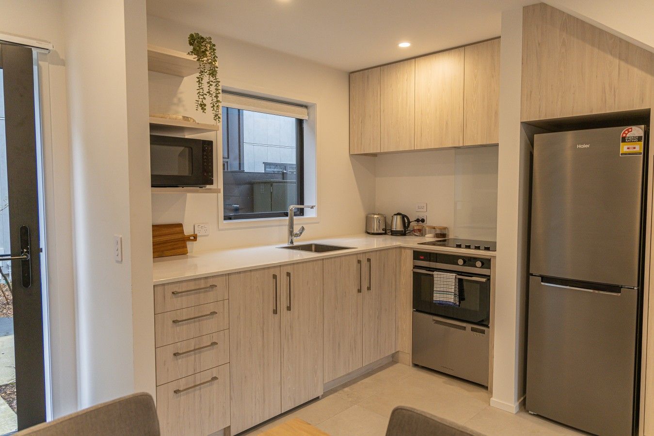 A modern kitchen with a stainless steel refrigerator, a microwave, a sink, and a stove.