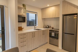 A modern kitchen with a stainless steel refrigerator, a microwave, a sink, and a stove.