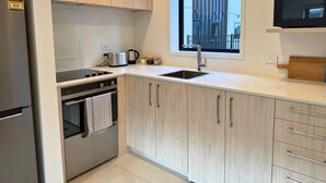 Una cocina moderna con horno integrado, refrigerador de acero inoxidable y una ventana sobre el lavamanos.