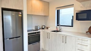 A modern kitchen with stainless steel appliances, light wood cabinets, and a window above the sink. - Modern 1BR Townhouse with Private Courtyard (Lower Hutt)