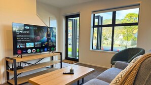 En moderne stue med tv, sofa og et vindue med udsigt.