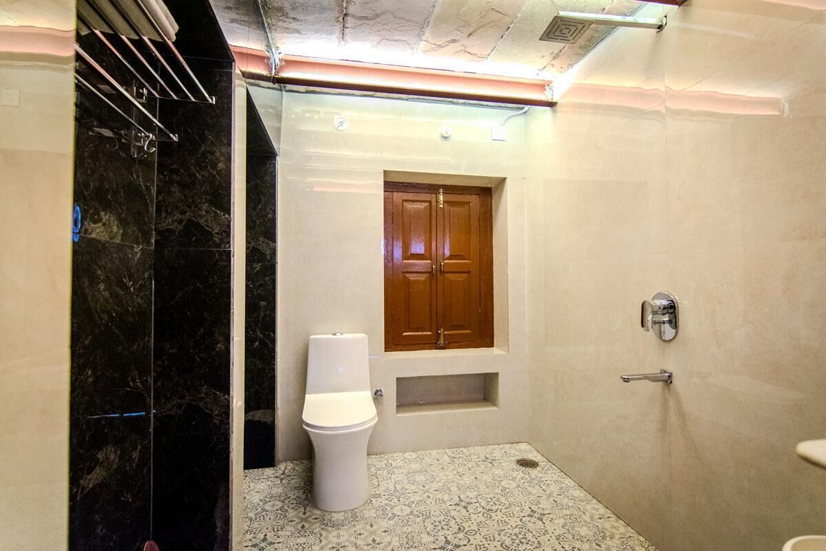 A bathroom with a toilet, a wooden door, and a shower area.