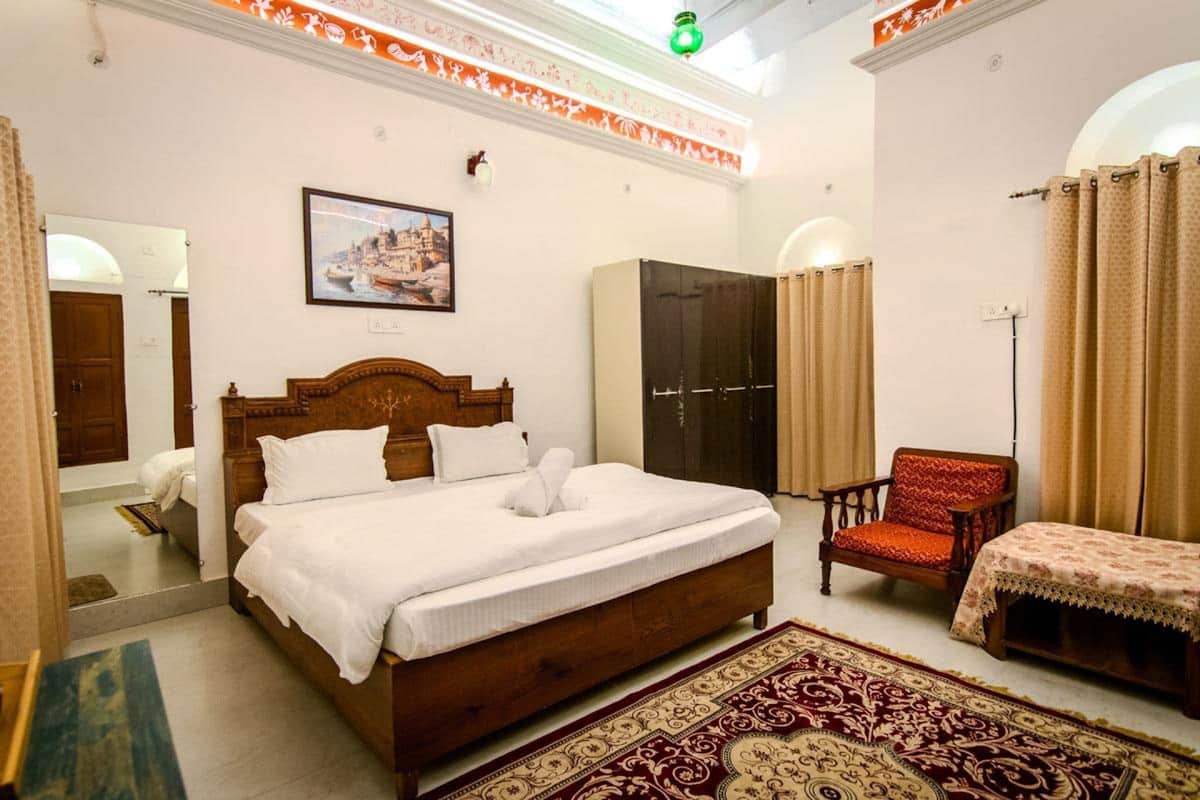 A bedroom with a large bed, a wardrobe, a chair, and a carpet.