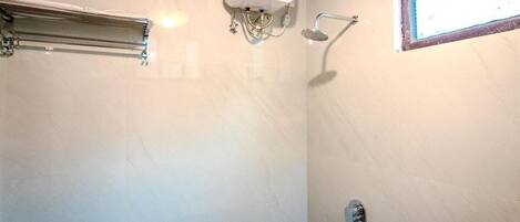 Un baño con ducha, toallero y ventana.