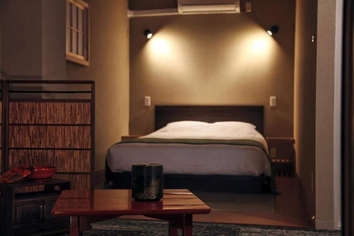 Un dormitorio con cama, mesitas de noche y aire acondicionado de pared.