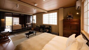 Une chambre de style japonais traditionnel, avec un sol recouvert de tatamis, un grand lit, des portes coulissantes et une vue sur l’extérieur.