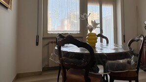 Un comedor con una mesa redonda, sillas y un florero con flores.