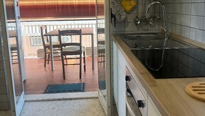 Una cocina con lavamanos, estufa y comedor con sillas.