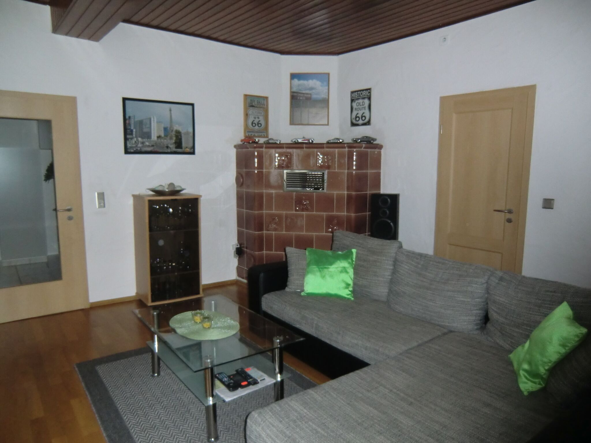 Ein Wohnzimmer mit einer Couch, einem Glastisch, einem Schrank und einer Tür.