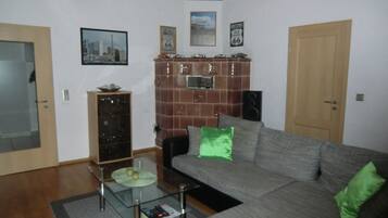 Ein Wohnzimmer mit einer Couch, einem Glastisch, einem Schrank und einer Tür.