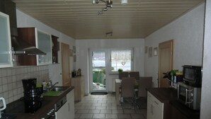 Cuina amb forns, rentapelats, armaris i zona de dinar amb cadires.