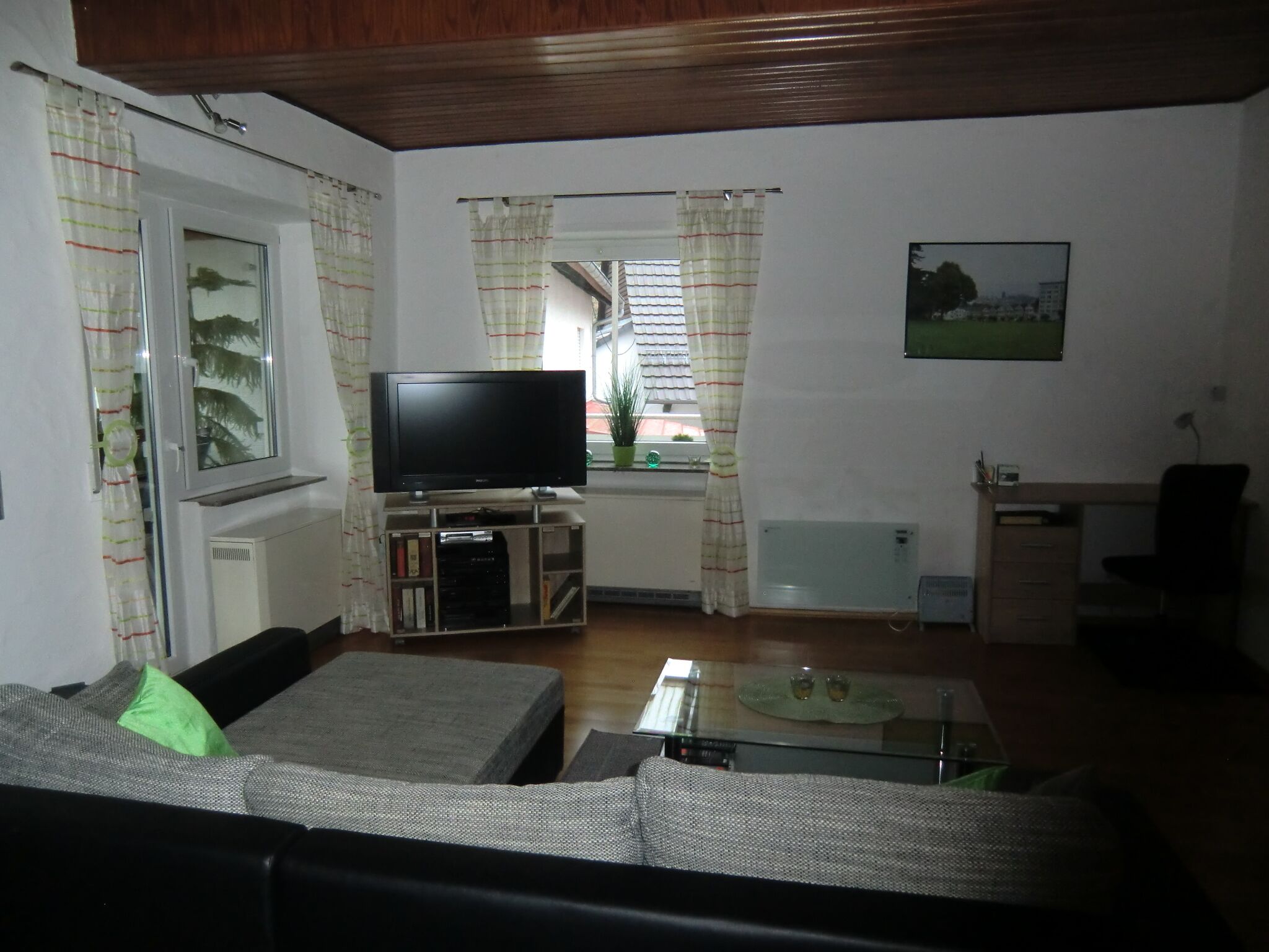 Ein Wohnzimmer mit Fernseher, Sofa und einem kleinen Tisch.