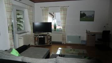 Ein Wohnzimmer mit Fernseher, Sofa und einem kleinen Tisch.