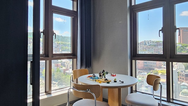Une pièce moderne avec une table ronde, deux chaises et de grandes fenêtres donnant sur la ville.