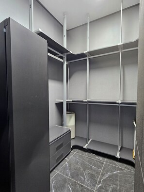Una habitación moderna y minimalista con estanterías empotradas, un armario gris y suelo de baldosas de mármol.