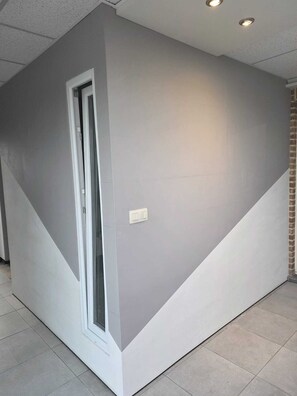 A room with a large window, a door, and a light switch on the wall.