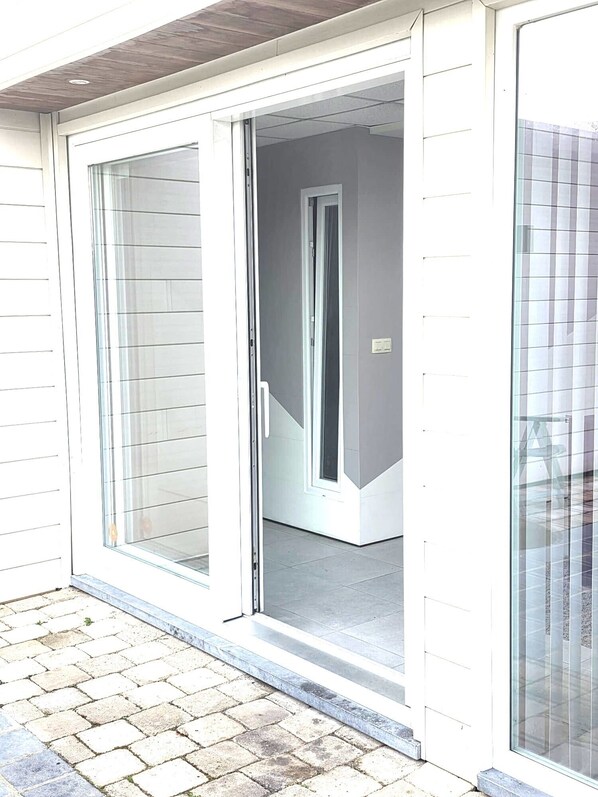 A residential entrance with a sliding glass door, a visible door frame, and a tiled patio area.